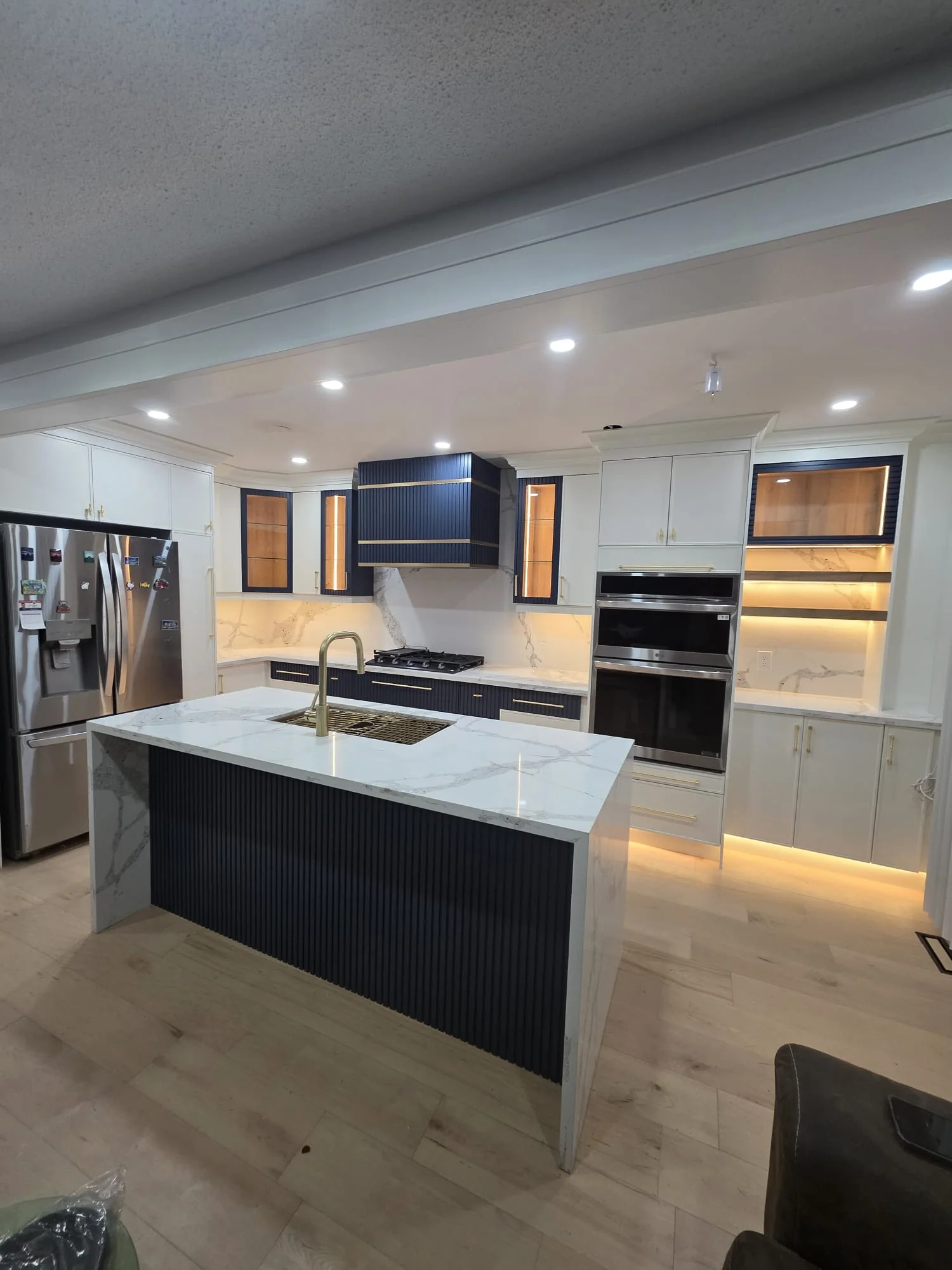 Completed white kitchen with custom cabinetry, stone counters and a contrasting island